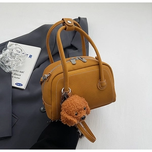 Détail du sac bowling en cuir jaune avec surpiqûres blanches et pendentif peluche