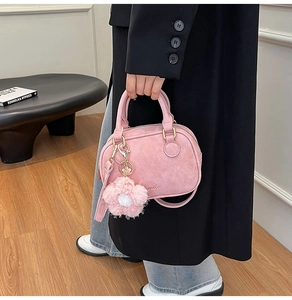 Detail of pink suede mini Boston bag with plush flower charm and gold hardware