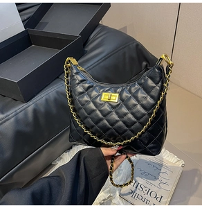 Détail macro du cuir matelassé noir et de la bandoulière en chaîne dorée du sac à main