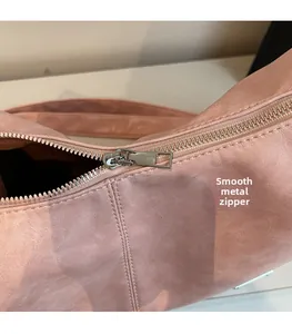 Close-up of smooth silver metal zipper and hardware on pink pebble leather bag