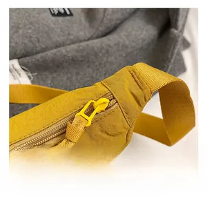 Close-up of yellow nylon crossbody bag with zipper detail and quality stitching