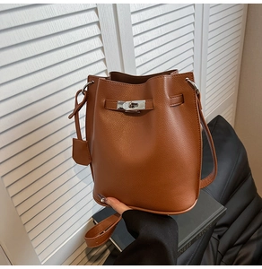 Close-up of brown pebbled leather bucket bag with silver twist lock and strap