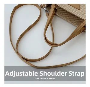 Close-up of adjustable leather strap and metallic buckle on beige woven tote bag