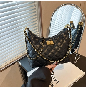 Détail d'un sac à bandoulière en cuir noir matelassé avec fermoir rotatif doré