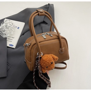 Détail du sac bowling en cuir marron avec doubles zips et pendentif chiot mignon