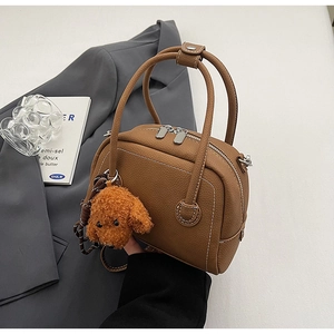 Détail du sac bowling en cuir marron grainé avec un charmant pendentif en peluche