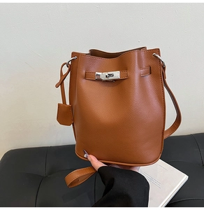 Detail of brown leather bucket bag with silver Kelly lock and litchi grain texture