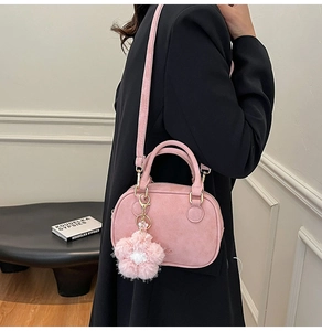 Pink suede-style handbag worn by model, featuring a cute floral plush charm detail