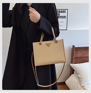Detail of camel woven tote bag featuring iconic triangular leather patch and strap