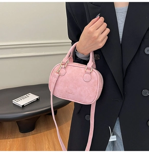 Pink velvet Boston bag with embroidery detail and slim shoulder strap on a model