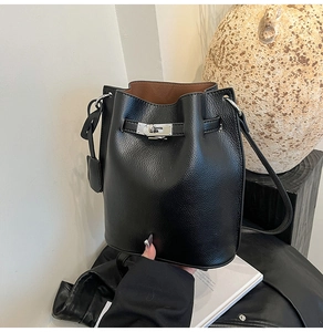 Close-up of black litchi grain leather bucket bag with silver buckle and brown lining
