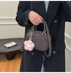 Detail of mocha brown satchel bag with gold hardware and pink floral plush charm