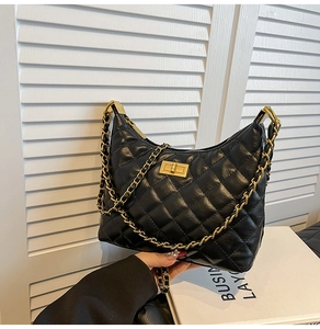 Gros plan sur le cuir matelassé et la chaîne dorée d'un sac à bandoulière noir