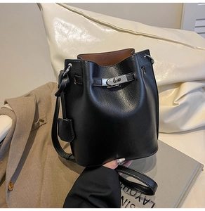 Detail view of black pebble leather bucket bag with silver metal buckle and tan lining