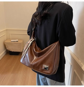 Detail of vintage brown tote bag featuring a decorative silk scarf and metal hardware