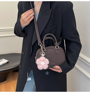 Detail of dark brown leather Boston bag with gold logo and pink plush flower charm
