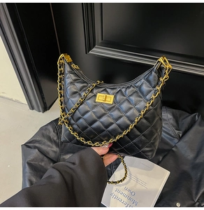 Gros plan d'un sac bandoulière matelassé noir avec chaîne dorée et fermoir métallique