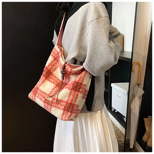 Detalle del bolso tote de felpa a cuadros rojos con textura suave y etiqueta de cuero