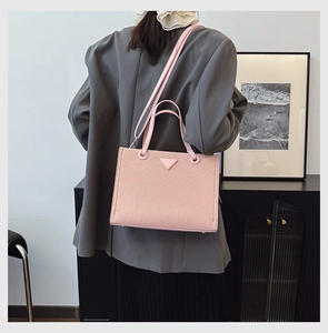 Pink woven texture tote bag with triangular detail shown on model in modern interior