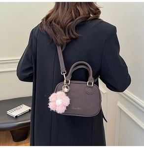 Detail view of dark brown PU leather crossbody bag with a cute pink plush flower pendant
