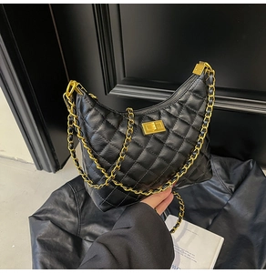 Détail de sac à bandoulière en cuir matelassé noir avec chaîne dorée et fermoir métallique