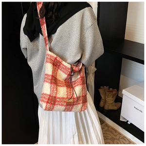 Detalle del bolso tote de felpa a cuadros rojos con textura y etiqueta de metal
