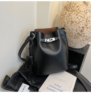 Detail showing pebbled black leather texture and silver buckle on a bucket bag