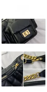 Detail of black quilted leather handbag with gold rectangular lock and metal chain strap
