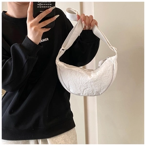 Detail of white nylon crescent bag showing pleated texture and adjustable shoulder strap