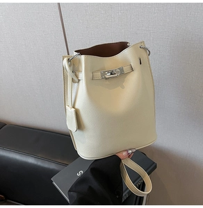 Close-up of cream lychee grain leather bucket bag featuring silver twist lock and drawstring