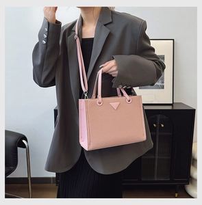 Detail of pink woven tote bag with adjustable shoulder strap shown in a lifestyle setting