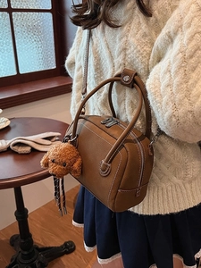 Sac bowling marron en cuir avec charme ours posé sur une table en bois naturel