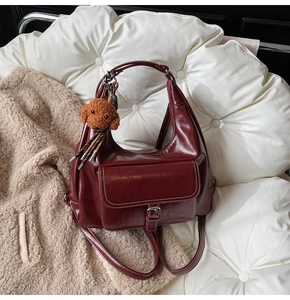 Détail d'un sac à dos en cuir rouge foncé brillant avec un charmant ours en peluche