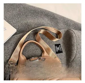 Detail of brown pebbled leather bag featuring a round handle and dual silver zip closures