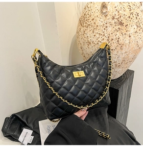 Détail du sac en cuir noir matelassé avec bandoulière chaîne dorée et fermoir pivotant