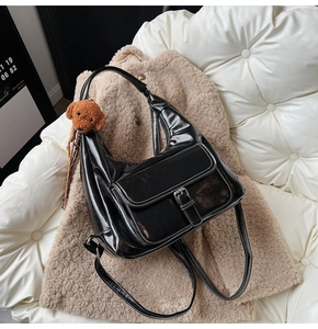 Détail du cabas en cuir verni noir avec charm ourson sur fond de manteau d'hiver