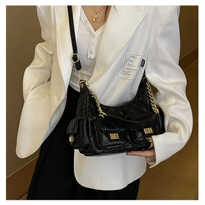 Detail of black quilted shoulder bag with golden chain straps and multi-pocket design