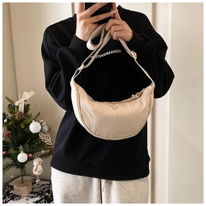 Detailed shot of cream nylon crescent crossbody bag with adjustable wide strap