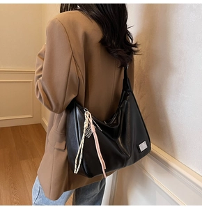 Detail of a black hobo shoulder bag with colorful rope tassel on a brown blazer model