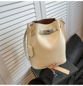 Detail of beige lychee leather bucket bag showing silver twist lock and interior contrast