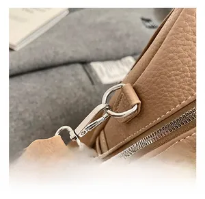 Detail of silver metal hook and white stitching on brown litchi pattern leather bag