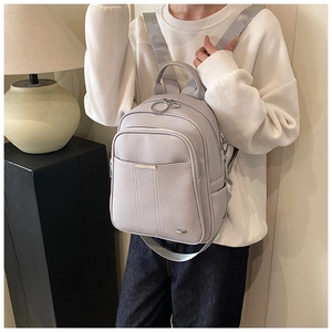 Detail view of a light gray pebble leather backpack featuring silver hardware and flap pocket