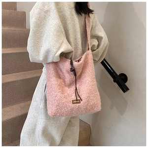 Primer plano del bolso tote rosa de lana de cordero con cordón y parche de cuero marrón