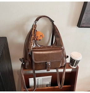 Sac hobo demi-lune marron foncé avec poche avant à boucle et breloque ours en peluche