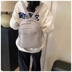 Detail of light grey backpack showing lychee grain leather texture and metal zipper puller