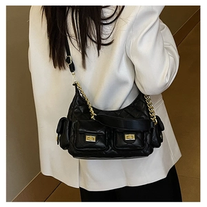 Close-up of black quilted chain shoulder bag with double pockets and gold hardware