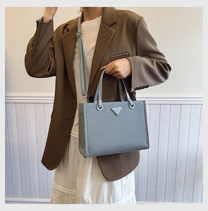 Close-up of light blue textured tote bag with top handle and adjustable shoulder strap