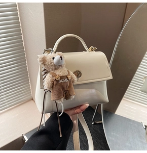 Detailed view of white crossbody bag with cute plush bear charm and metallic clasp