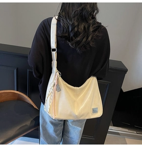 Detail of cream white tote bag featuring woven knot charm and pink tassel accent