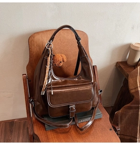 Gros plan sur un sac Hobo marron brillant avec coutures contrastées et charm d'ours en peluche